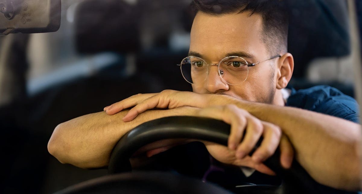 Kierowca w okularach nocnych prowadzi samochód po ciemnej autostradzie z reflektorami mijających aut