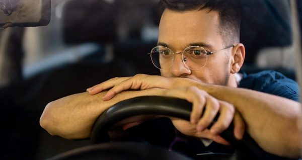 Kierowca w okularach nocnych prowadzi samochód po ciemnej autostradzie z reflektorami mijających aut